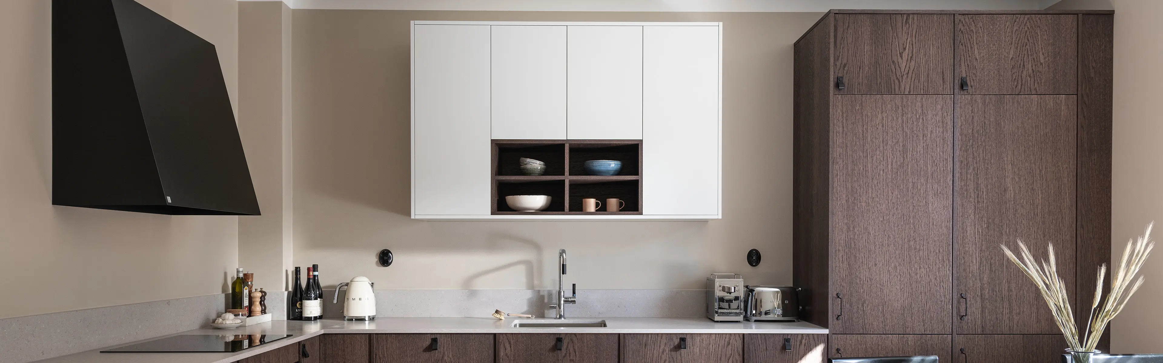 Svart veggmontert kjøkkenventilator i kjøkken med kjøkkeninnredning i mørkt treverk.