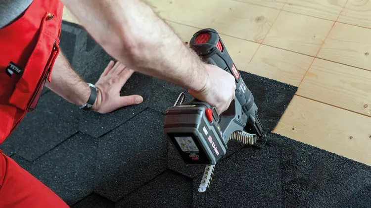 Håndverker som viser hvordan legge takshingel med spikerpistol.