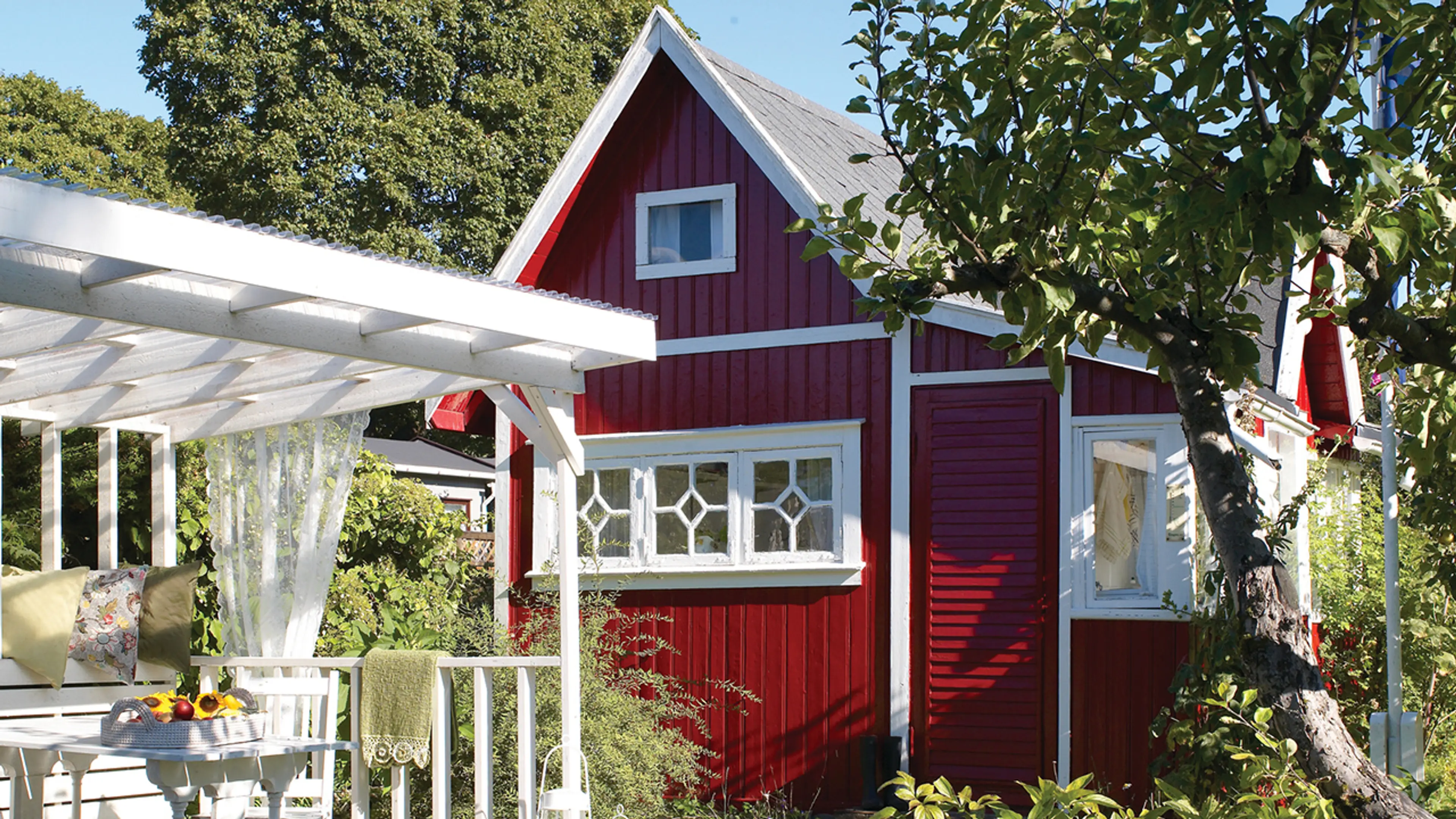 Lite hus i hage malt med akrylmaling Jotun Optimal i fargen 2142 Vestlandsrød og 1001 Egghvit på dører og vindu.