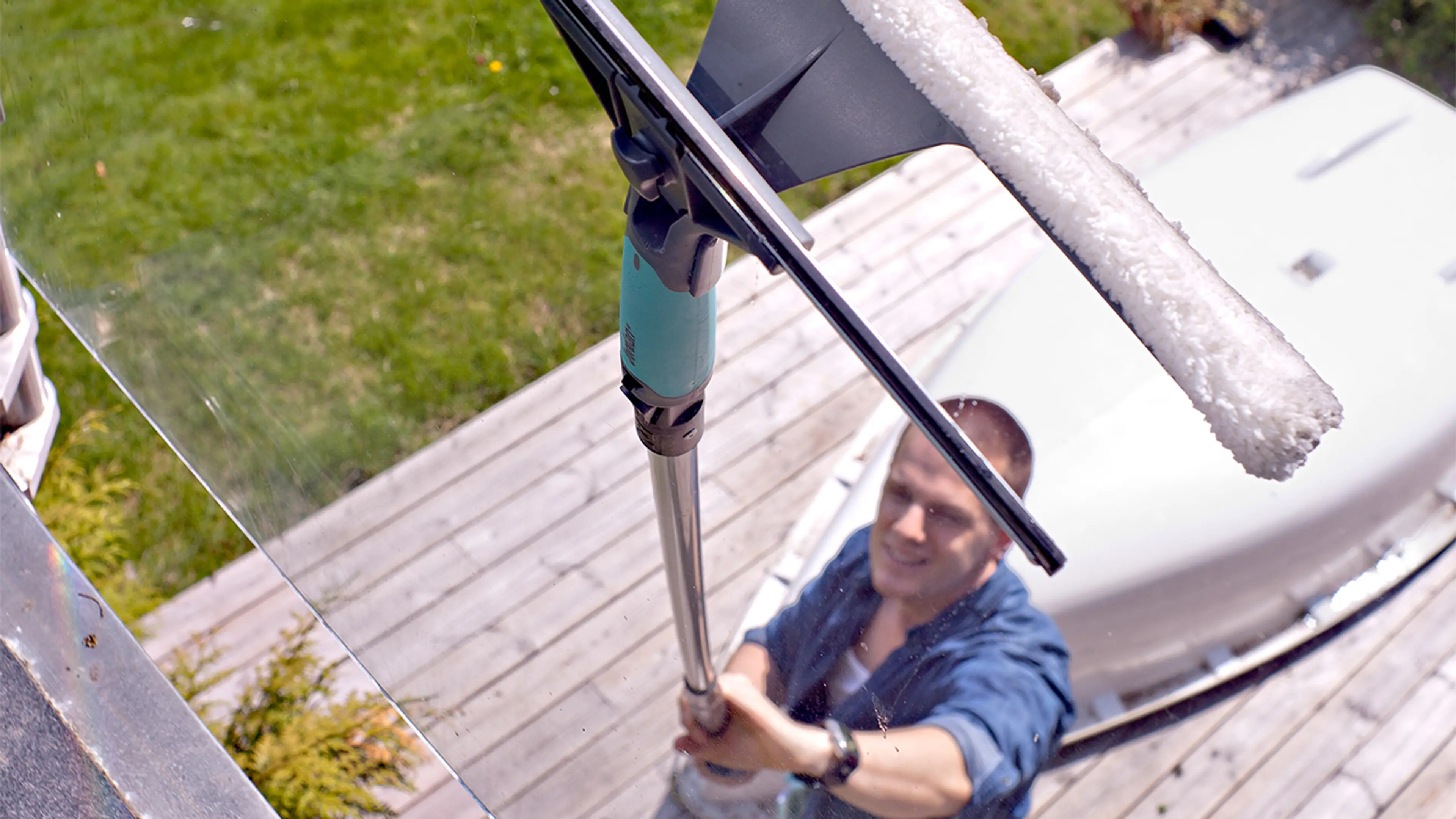 Mann som vasker vindu ute med forlengerskaft til glassflater høyt oppe.