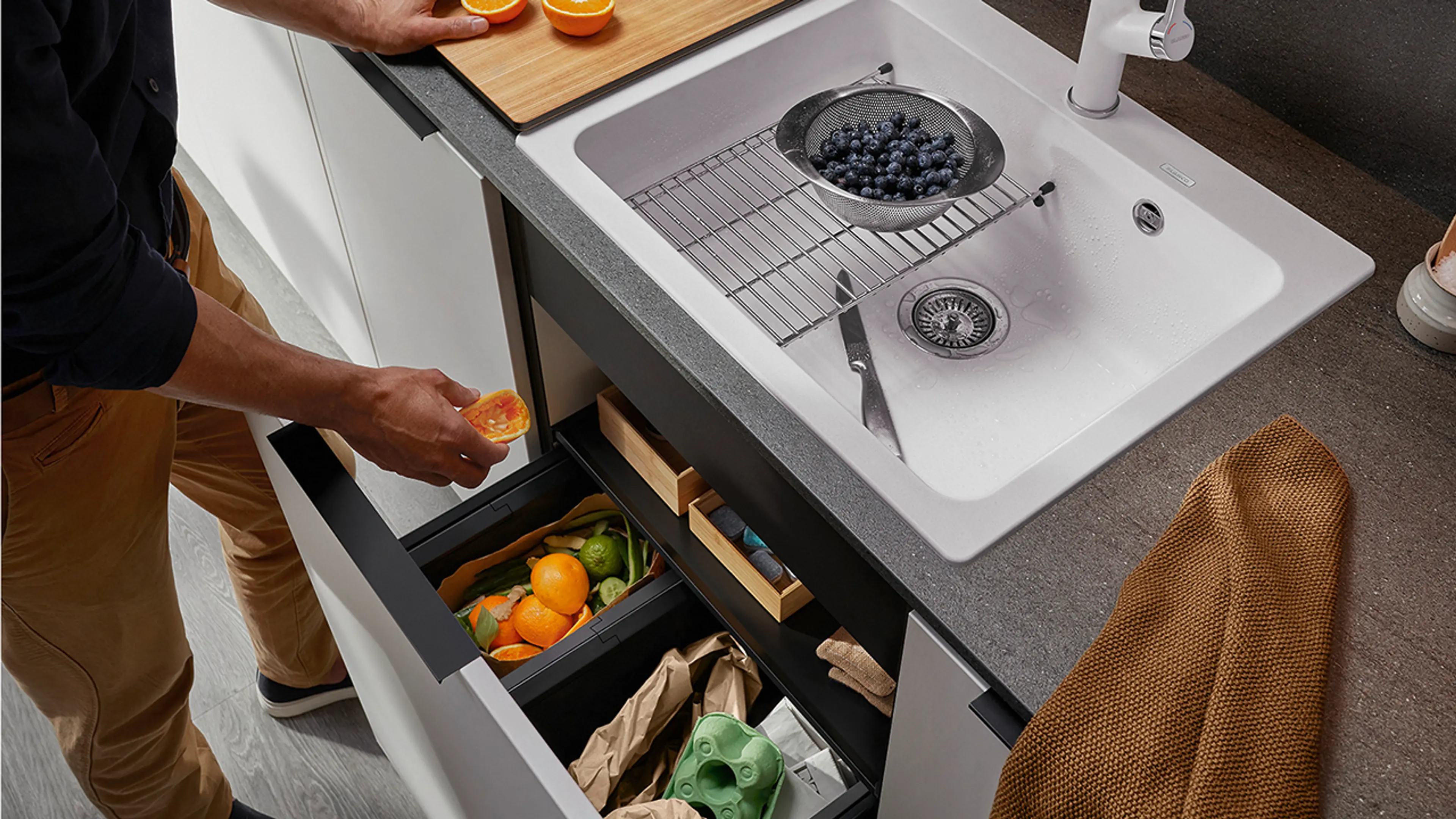 Smart avfallssortering på kjøkkenet under vasken og mann som kaster i matavfall.