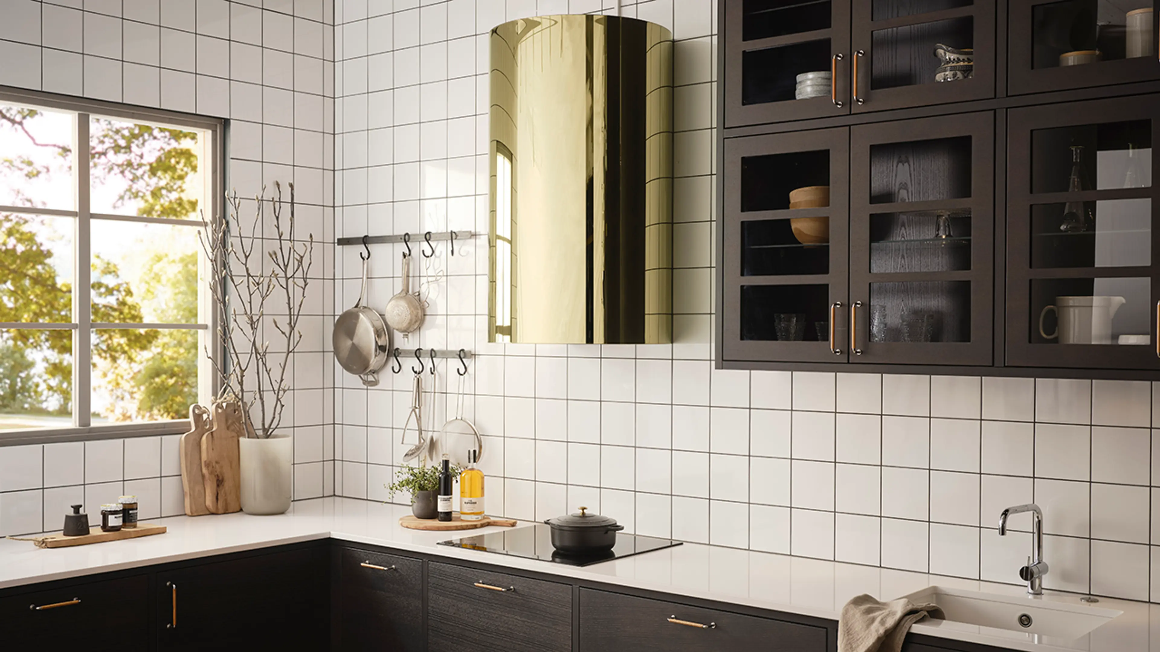 Kjøkkenvifte i messing på hvitt og brunt kjøkken med fliser på veggen.