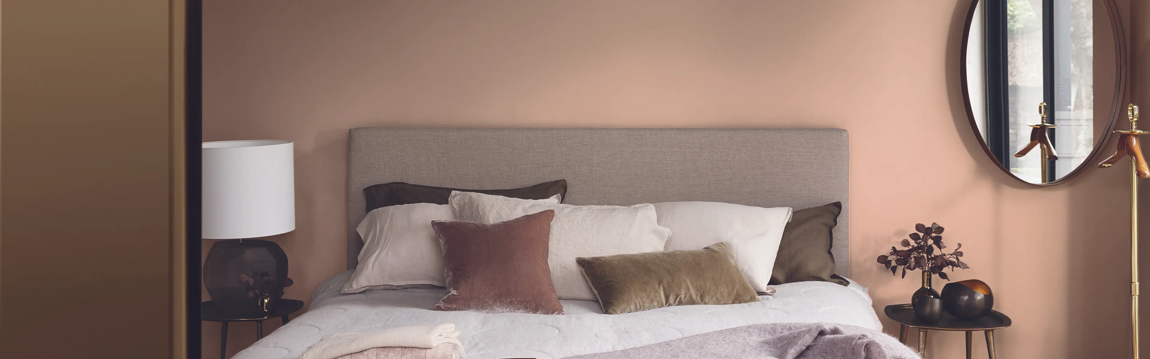 Hotellfølelse på soverommet med brune vegger og stor dobbeltseng med fluffy puter.