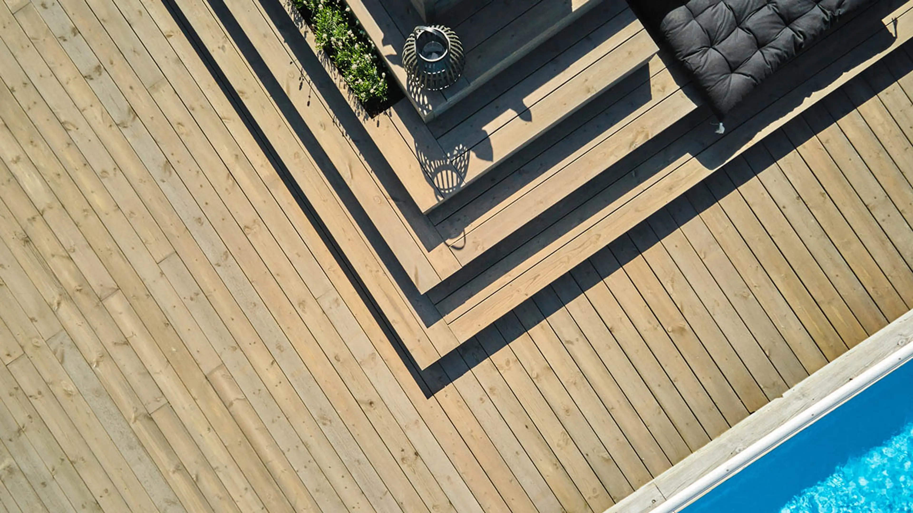 Stor lys brun terrasse med trapp og basseng.