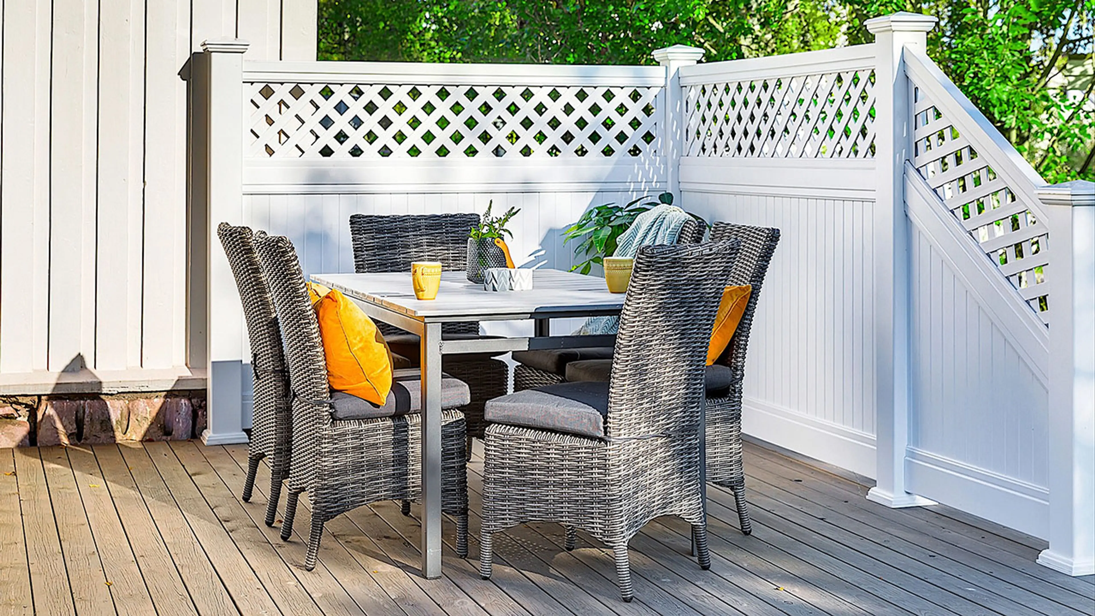 Skjermet terrasse med hvit klassisk levegg og spisegruppe.
