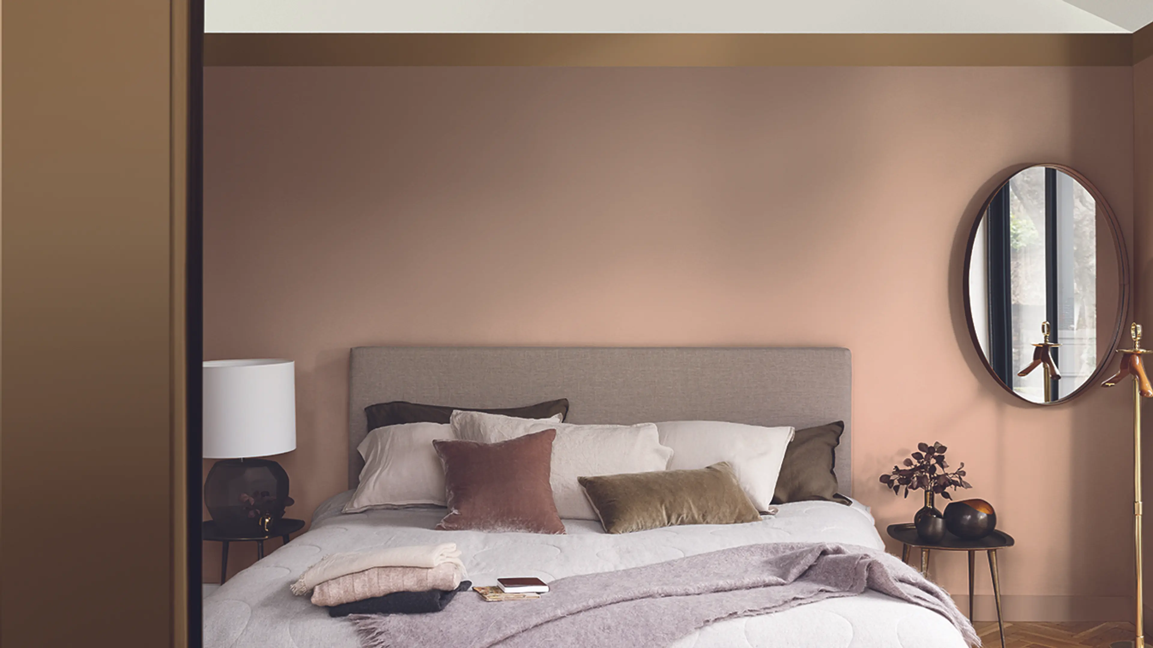 Hotellfølelse på soverommet med brune vegger og stor dobbeltseng med fluffy puter.