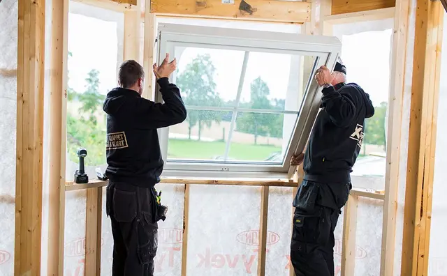 to håndverkere fra XL-BYGG setter inn et vindu i et nybygg