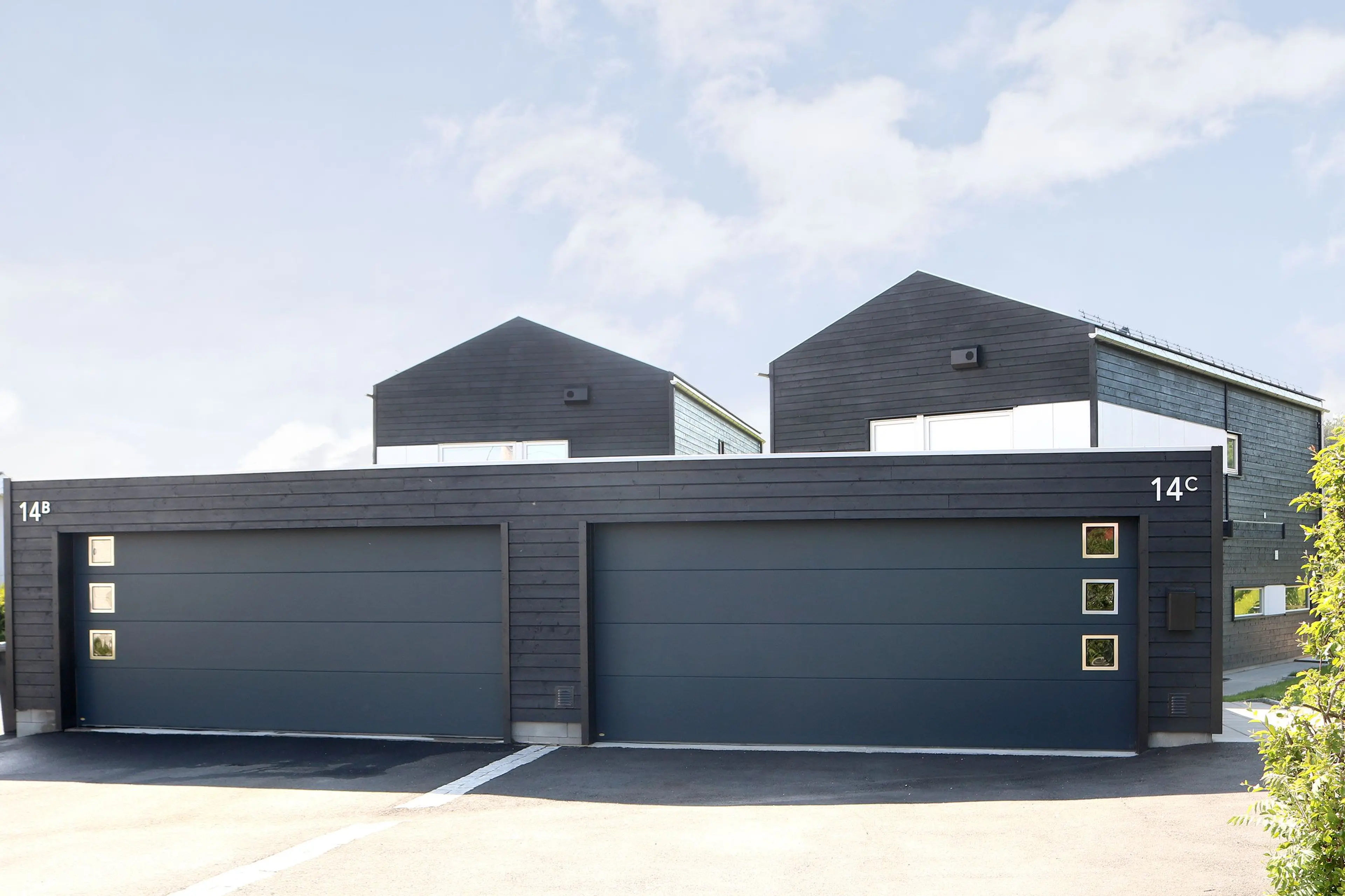 To moderne eneboliger med hver sin garasje med sorte, isolerte garasjeporter