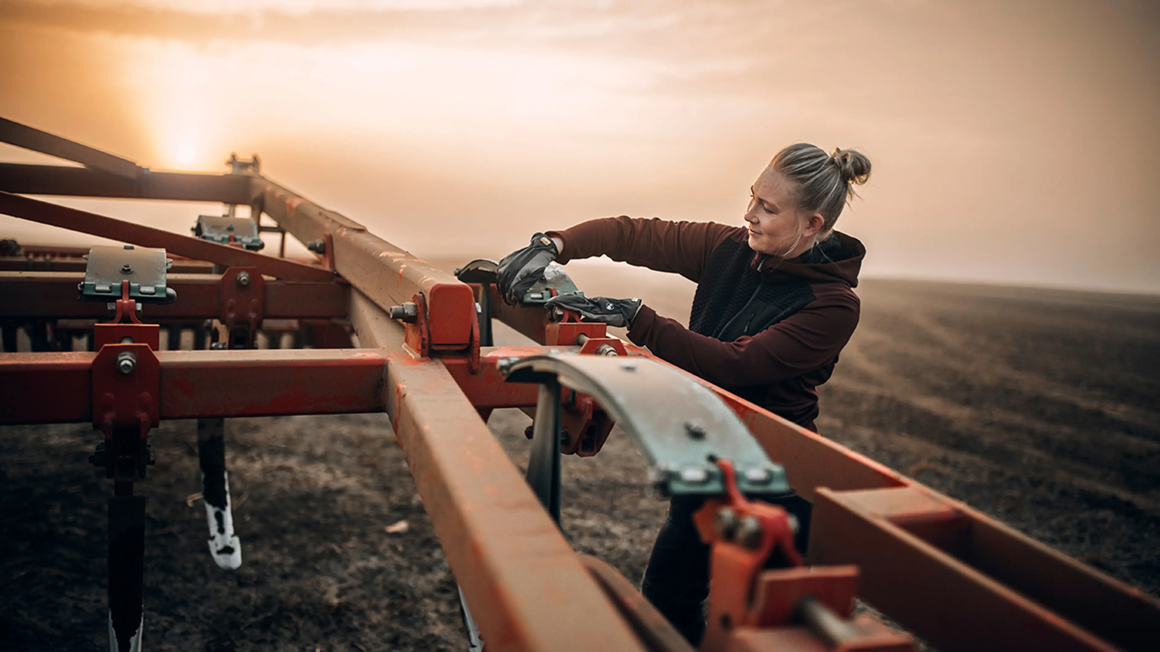 Kvinne som justerer på kjøretøy på et jorde med arbeidsklær fra Blåkläder.