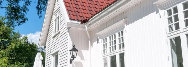 Hvitt hus med rød takstein.