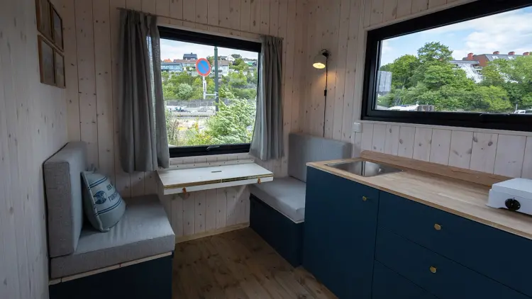Innredning i minihytte med sittegruppe, kjøkken og vinduer.