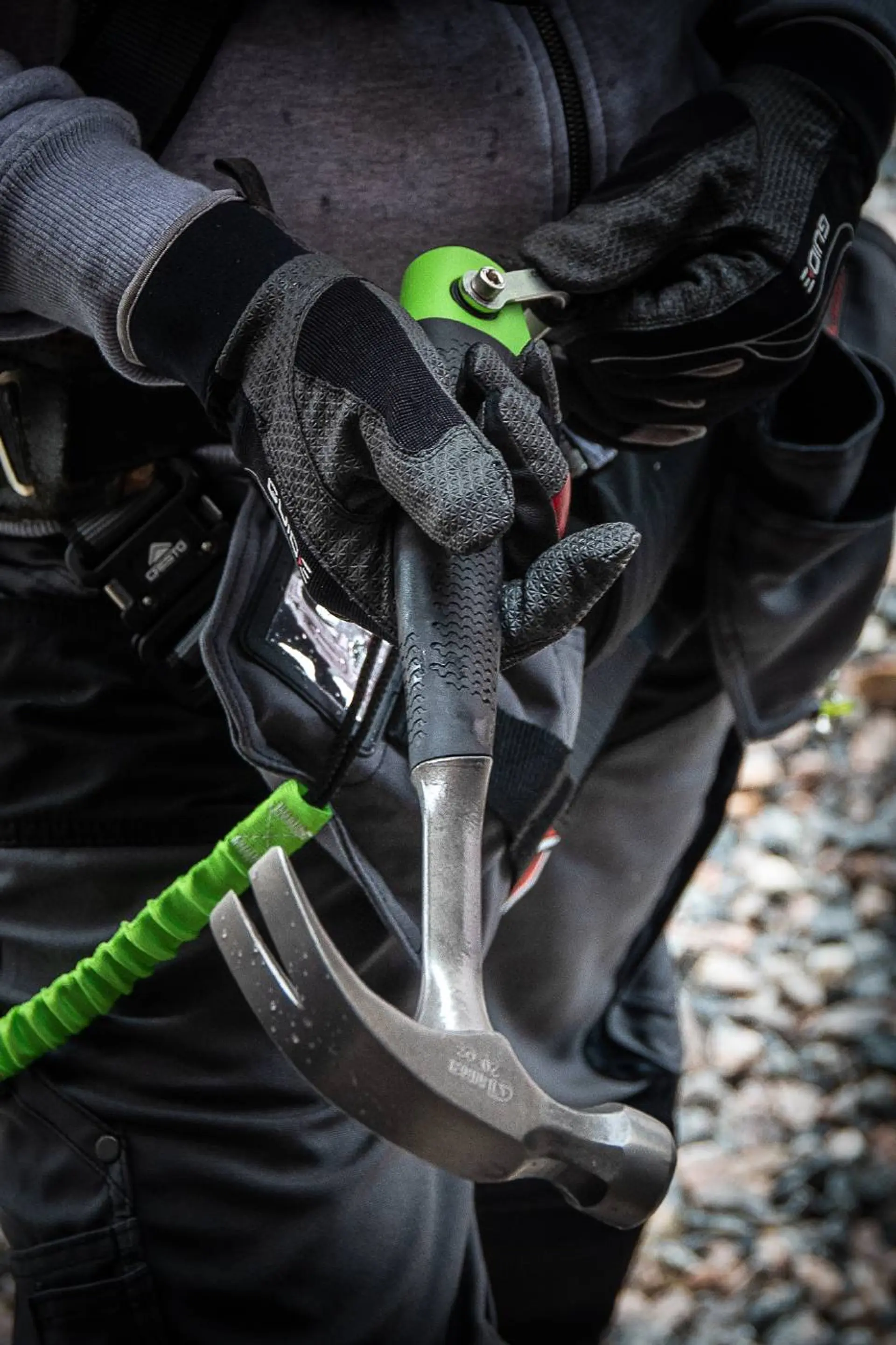 Snekker holder i en sort og grønn snekkerhammer fra Luna Tools, med verktøysikring
