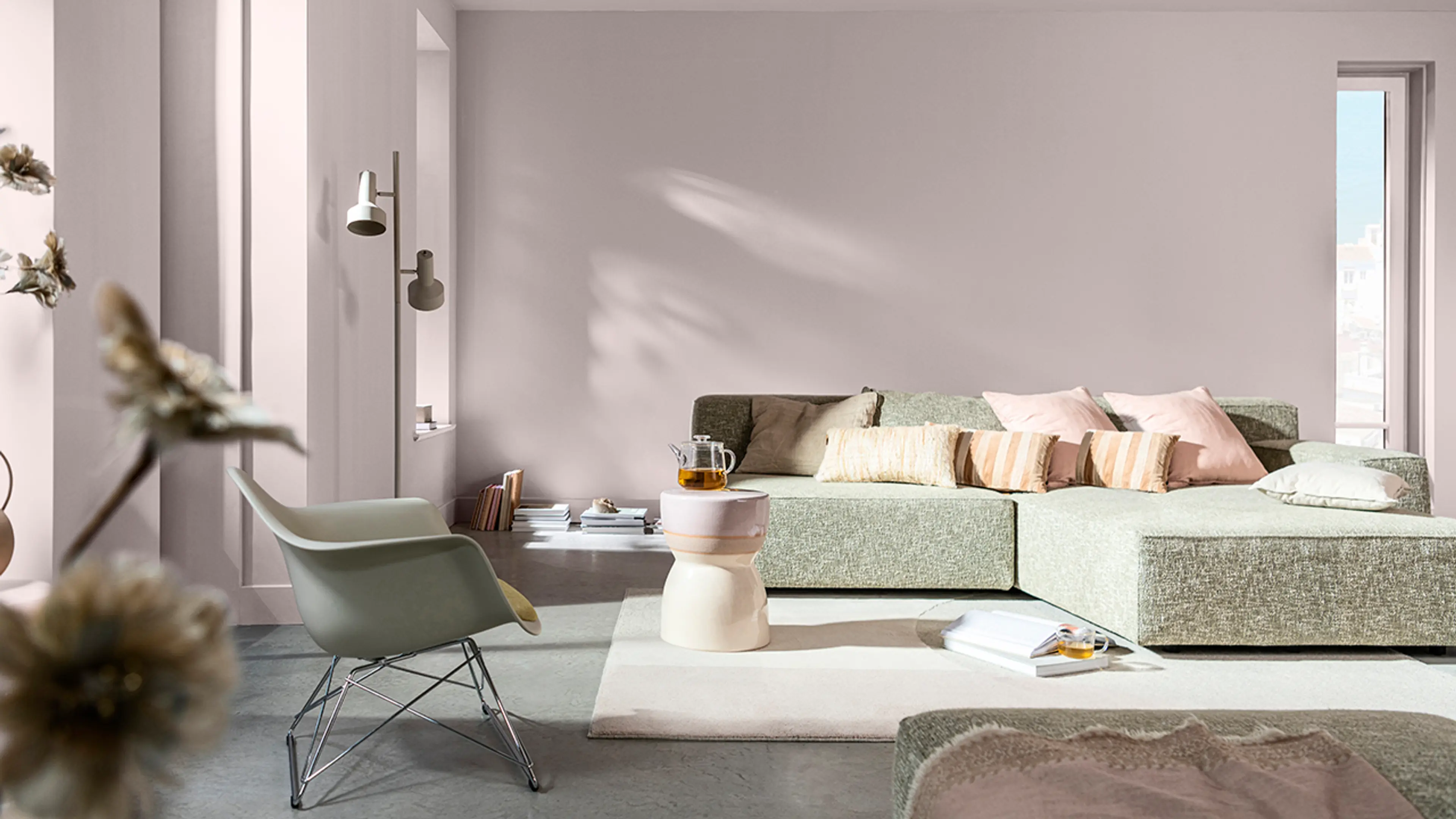 Stue med grå møbler og lyserosa vegger.