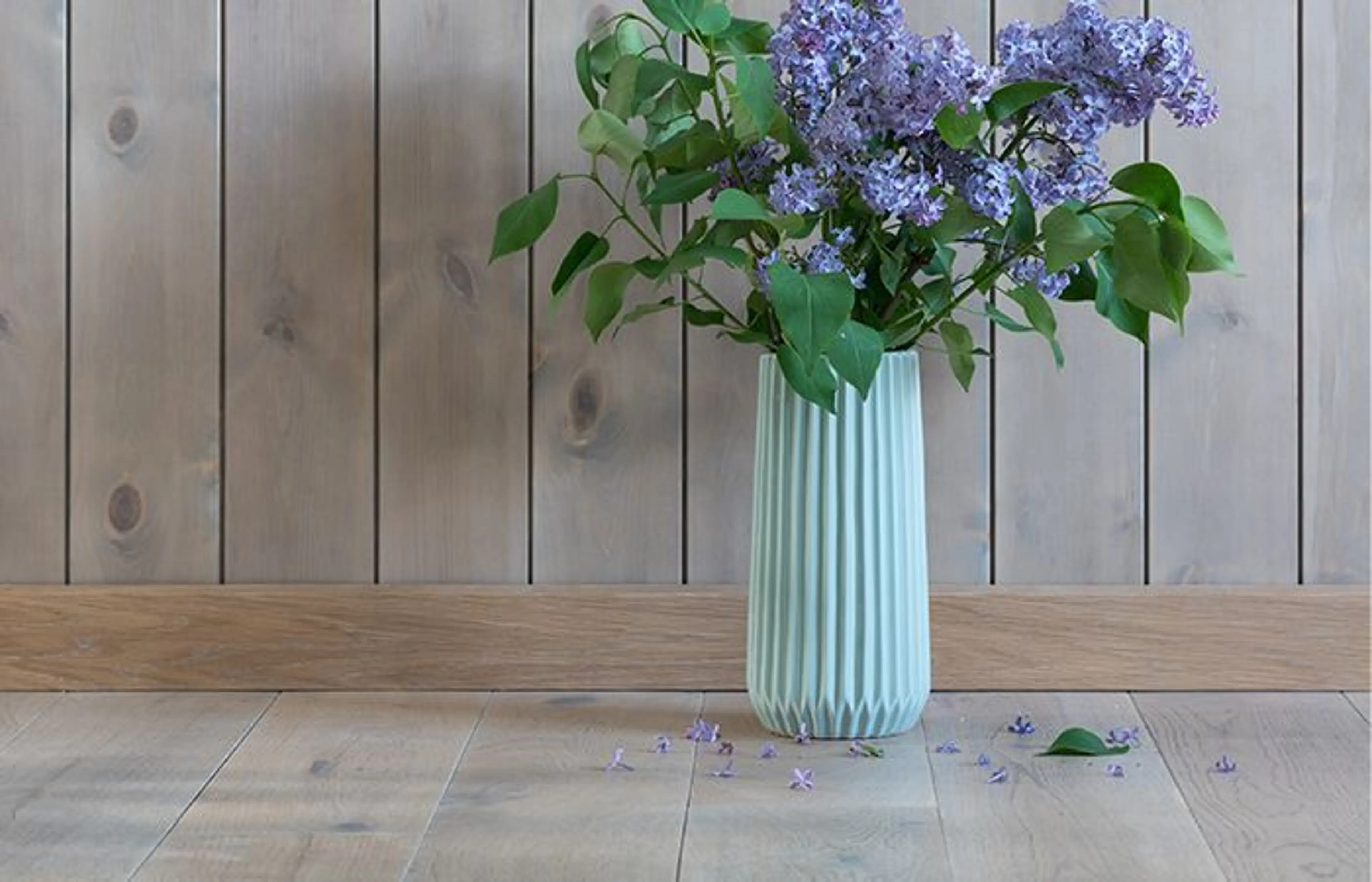 en vase med blomster står på gulvet