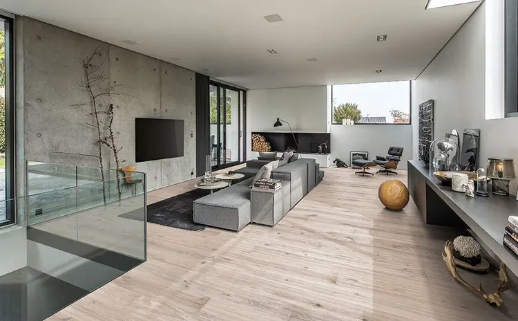 moderne stue med betongvegger, parkettgulv og glassrekkverk