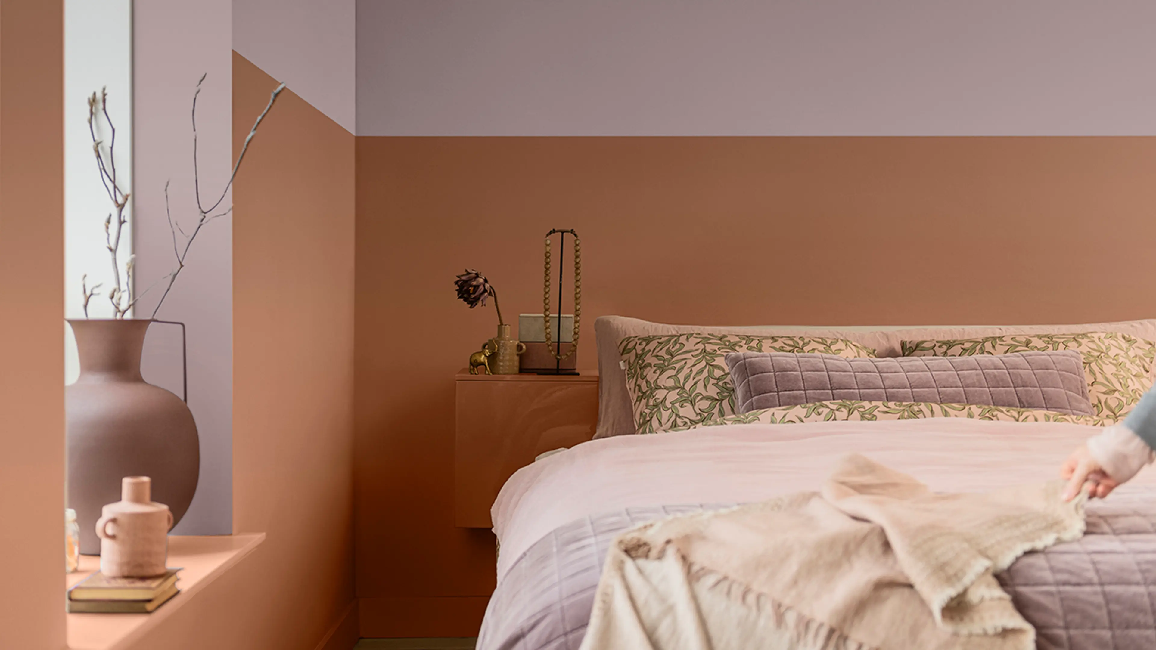 Soverom med oppredd seng og Sweet Embrace fra Norsjö kombinert med en terrakottafarge på veggen.