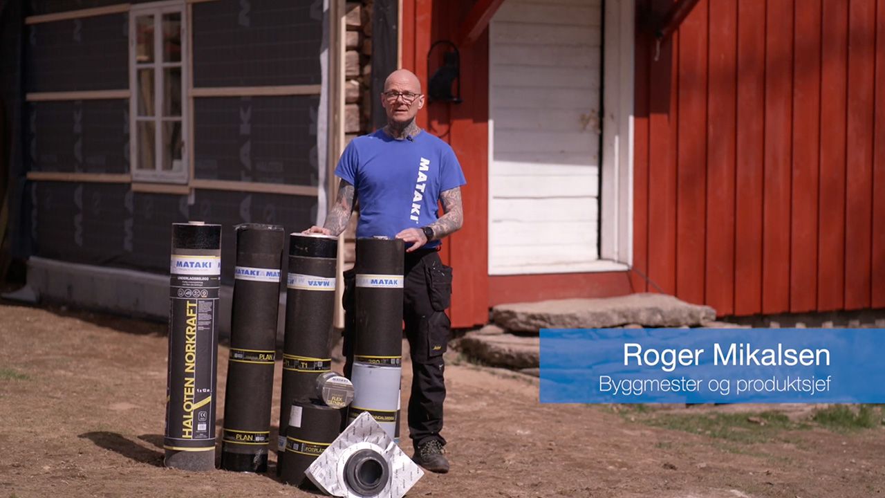 Mann som viser frem undertaksbelegg foran et rødt hus.