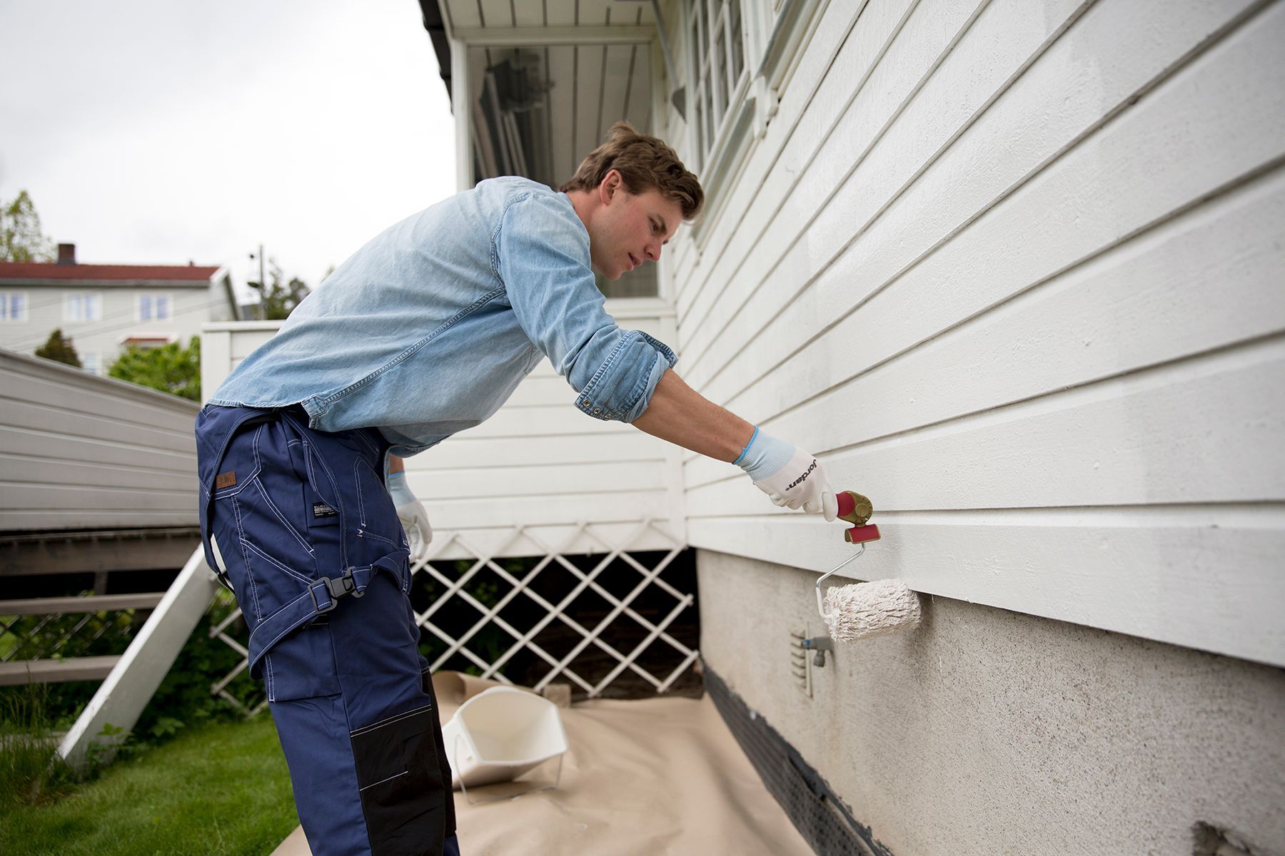 Mann maler fasaden på et hus med malingsrulle fra Jordan
