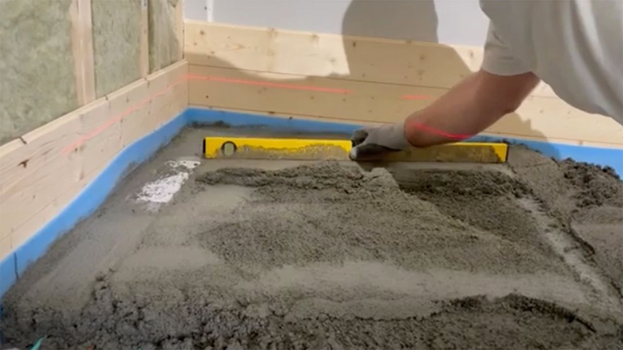 Håndverker som støper med krympfri støp spesielt utviklet for gulv i våtrom.