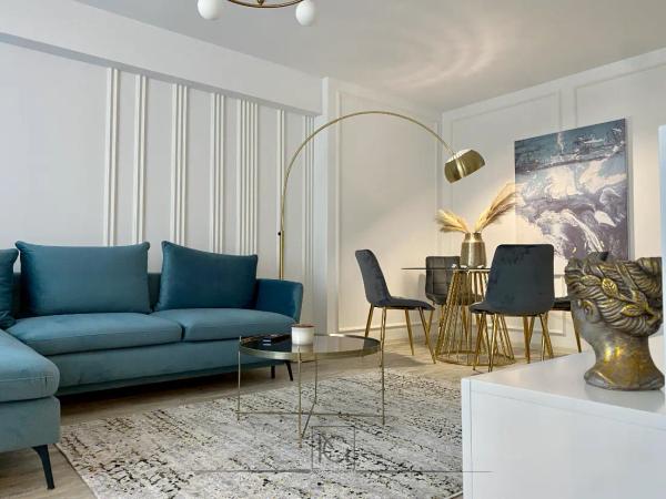 Living deschis cu canapea turcoaz, comodă albă și sculptură aurie de cap – Apartament A.T., București