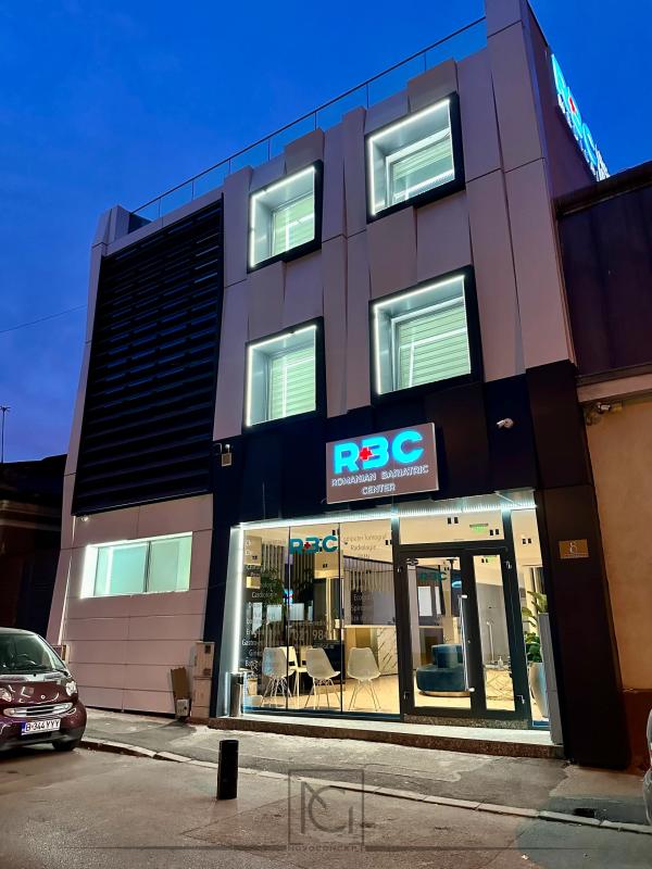Fațada renovată seara, cu ferestre iluminate și recepția vizibilă prin vitrină – Romanian Bariatric Center, București