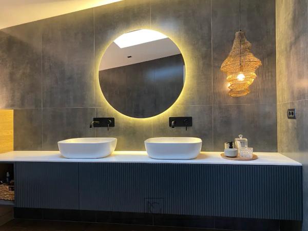 Baie cu două lavoare, oglindă rotundă iluminată și mobilier albastru riflat – Casa A.M., Bragadiru