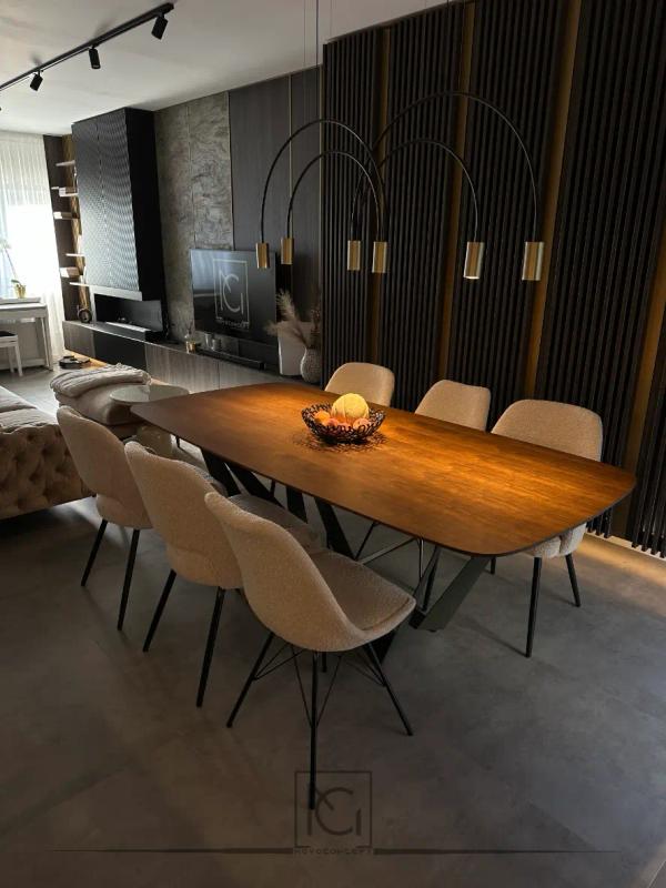 Masă de dining din lemn cu scaune bej, perete cu lamele închise și lustră arcuită – Casa A.M., Bragadiru