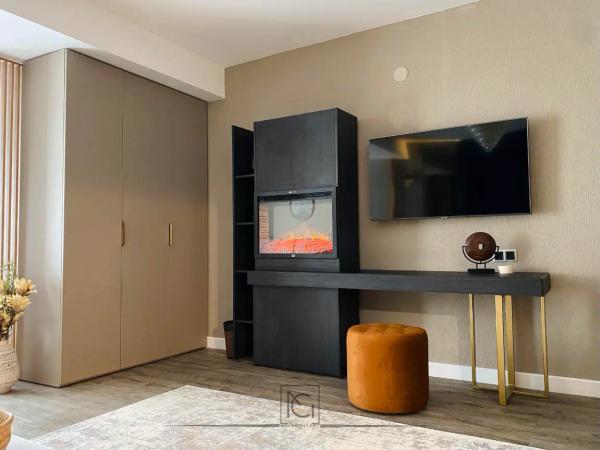 Cameră de hotel cu dulap bej, perete TV cu șemineu electric negru și taburet portocaliu – Elexus Poiana Brasov, Brașov