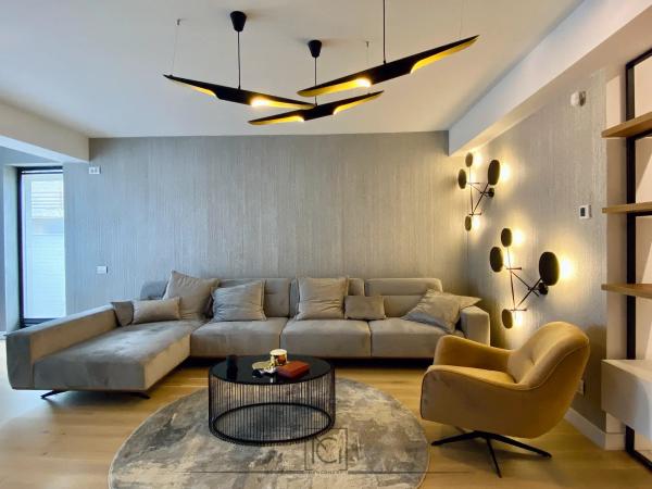 Living cu canapea modulară gri, covor rotund și lustră neagră cu interior auriu