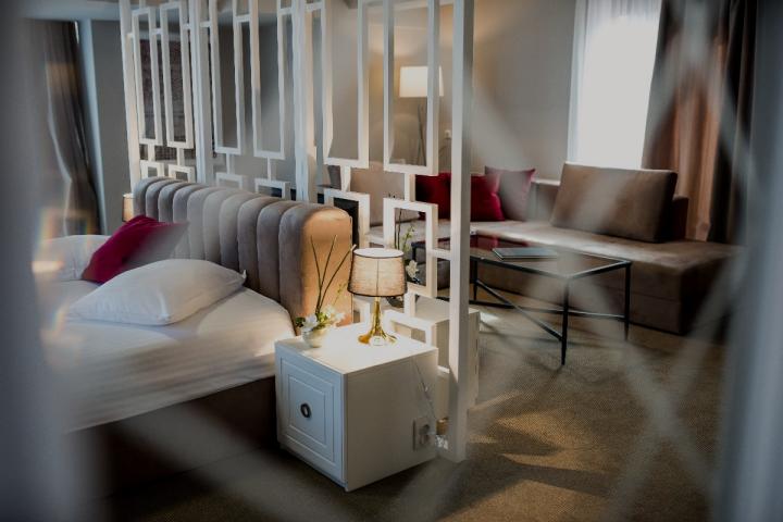 Cameră de hotel cu tăblie capitonată și paravan decorativ alb, văzută printr-un panou traforat – Hotel Boavista, Timișoara