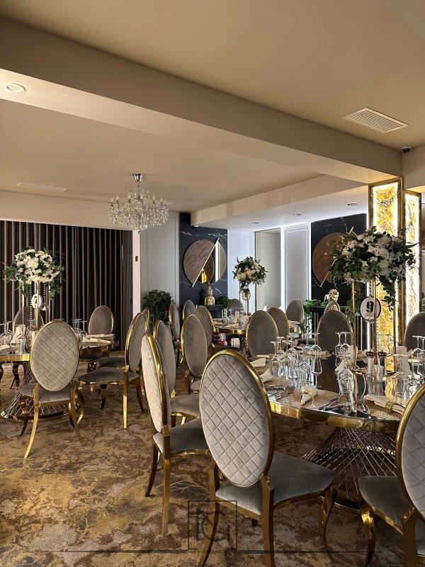 Salon de evenimente cu scaune gri capitonate cu ramă aurie și lustră de cristal
