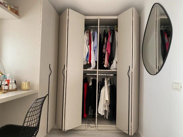 Dulap cu uși pliante deschise, haine pe umerașe și oglindă asimetrică neagră – Casa A.M., Bragadiru