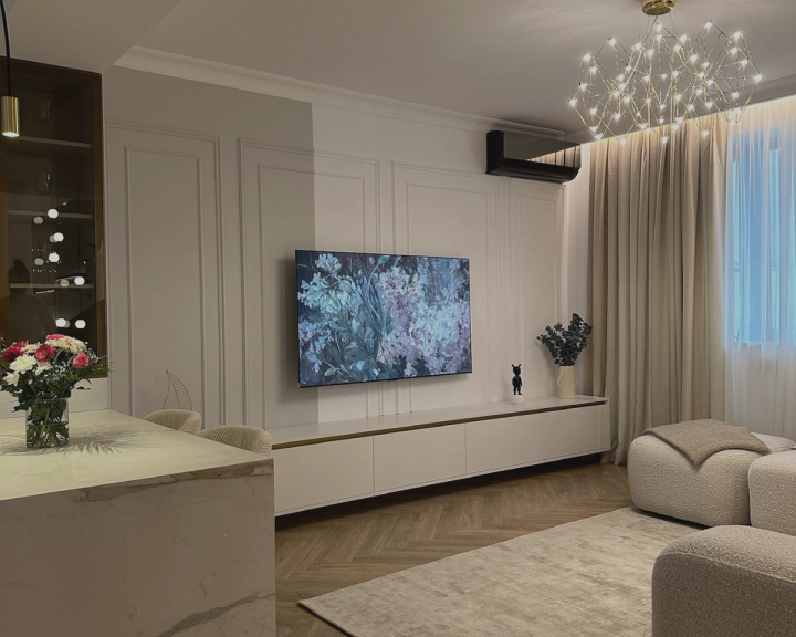 Living luminos cu comodă TV albă, pereți cu baghete decorative și lustră modernă din fire