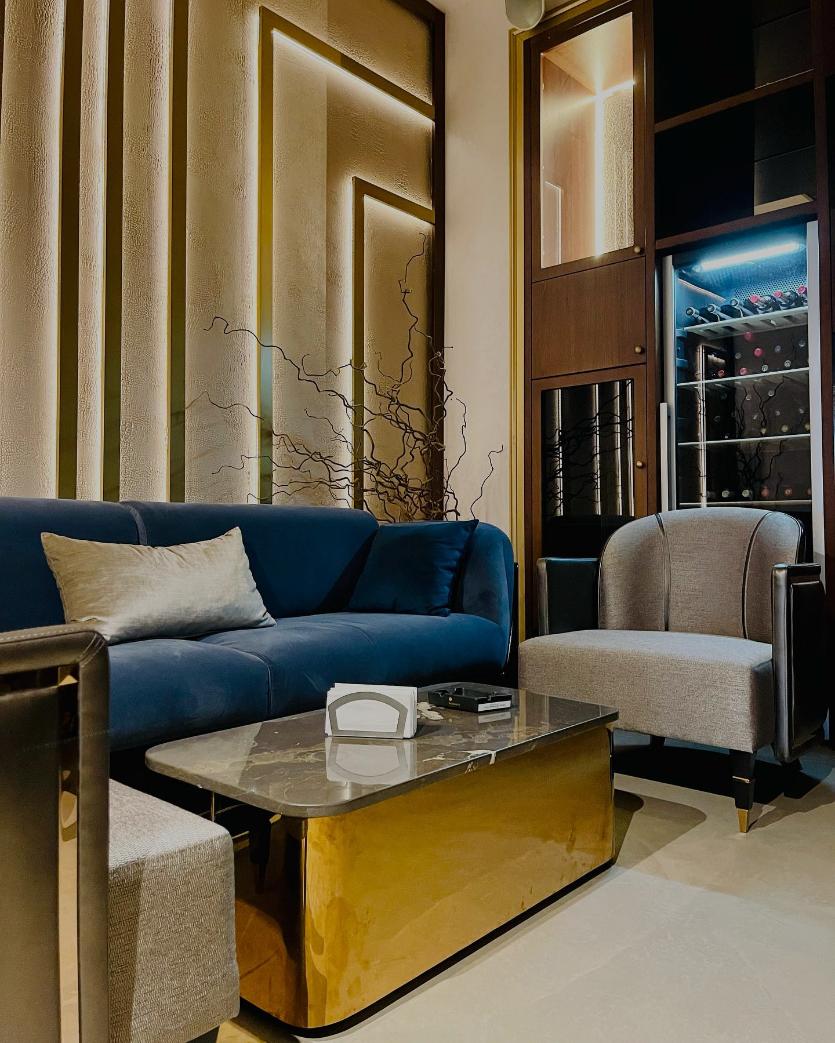 Lounge cu canapea albastră din catifea, măsuță aurie și perete decorativ cu iluminat ascuns