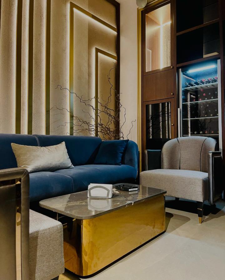 Lounge cu canapea albastră din catifea, măsuță aurie și perete decorativ cu iluminat ascuns
