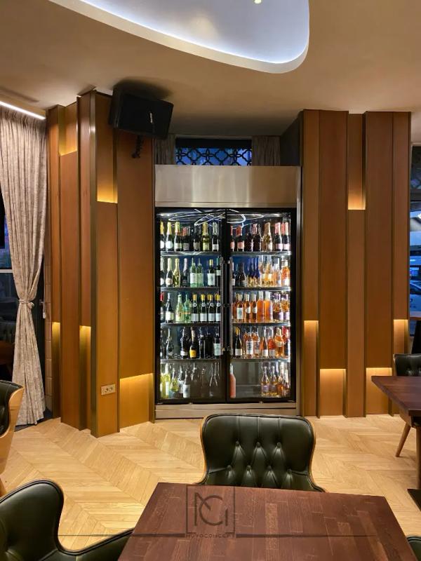 Vitrină frigorifică de vinuri între panouri din lemn cu iluminat vertical – Lido's Brasserie by Arogant, București