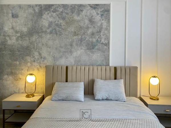 Pat dublu cu tăblie bej capitonată, două veioze aurii și perete cu tapet texturat – Apartament A.T., București