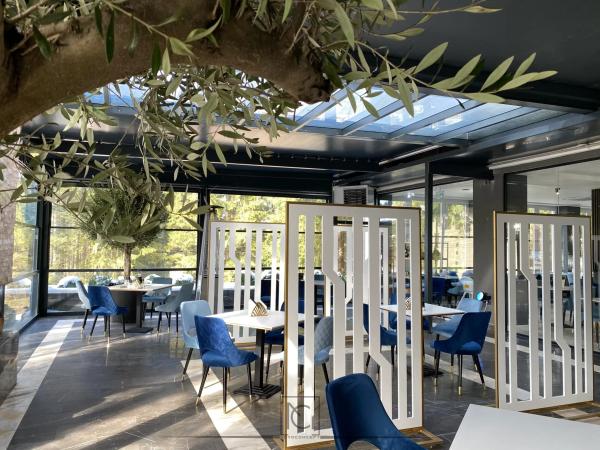 Terasă închisă de restaurant cu paravane albe traforate și scaune albastre