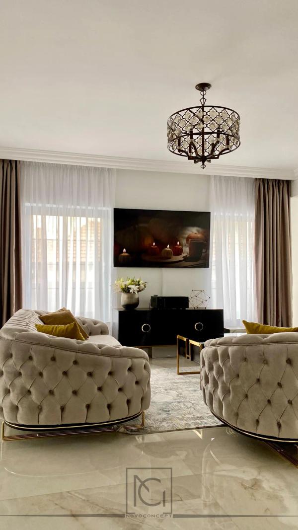 Living cu canapele capitonate crem, lustră de cristal și pardoseală lucioasă din marmură