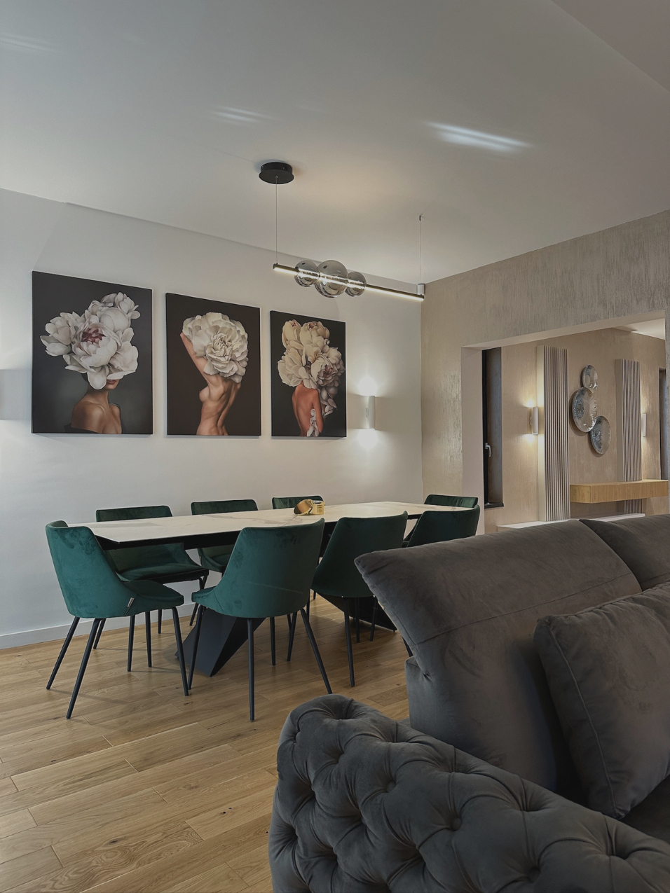 Zonă de dining cu scaune verzi din catifea, tablouri cu flori și canapea gri capitonată – Casa A.M., Alexandria