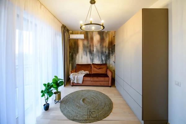 Cameră cu canapea cărămizie, covor rotund din iută și dulapuri gri până la tavan – Apartament Park View, București