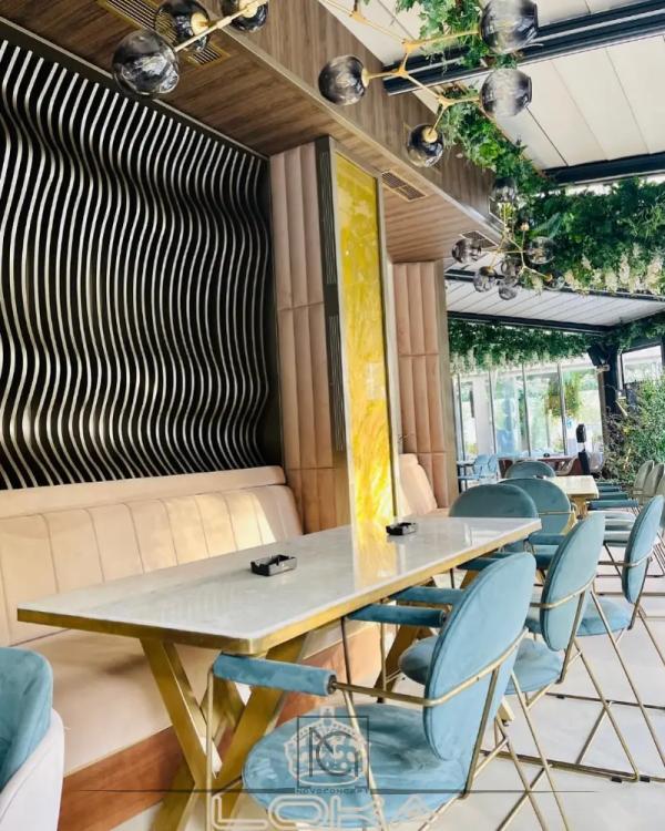 Terasa LOKA Lounge cu banchetă tapițată, scaune turcoaz și perete negru cu lamele ondulate