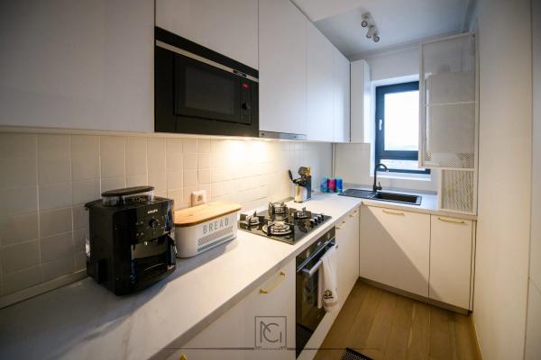 Bucătărie albă cu mânere aurii, microunde încorporat și faianță albă – Apartament Park View, București