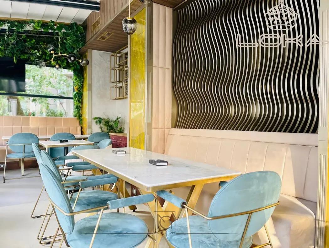 Zonă de dining în LOKA Lounge cu scaune turcoaz, masă din marmură și perete cu lamele ondulate