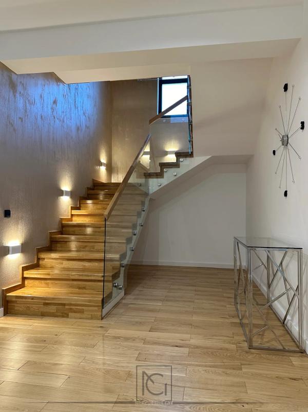 Scară interioară din lemn cu balustradă din sticlă și aplice cu lumină caldă