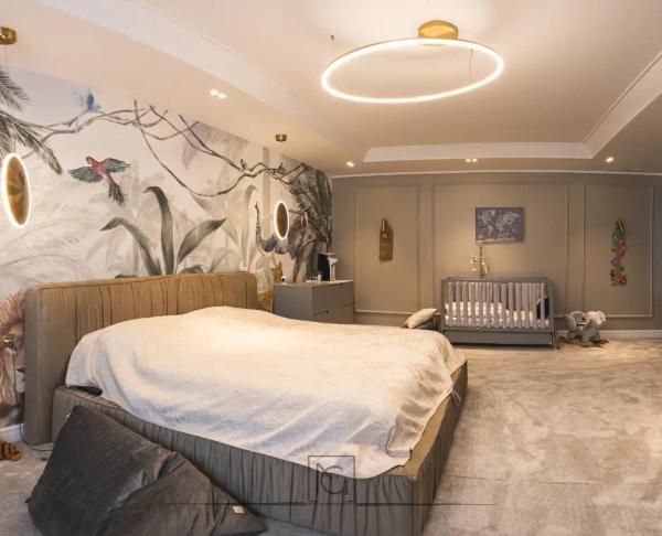 Dormitor cu tapet cu păsări și plante, pat tapițat bej, pătuț și lustră inelară – Penthouse B. V., București