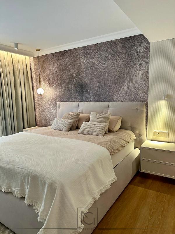 Dormitor cu pat crem capitonat, tencuială decorativă și perete riflat iluminat – Casa A.A., București