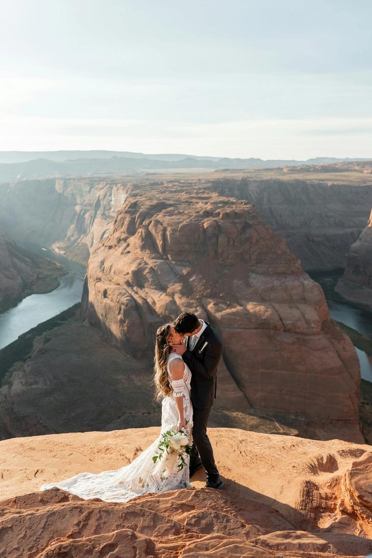 Bride and groom kissing on a canyon overlook at golden hour