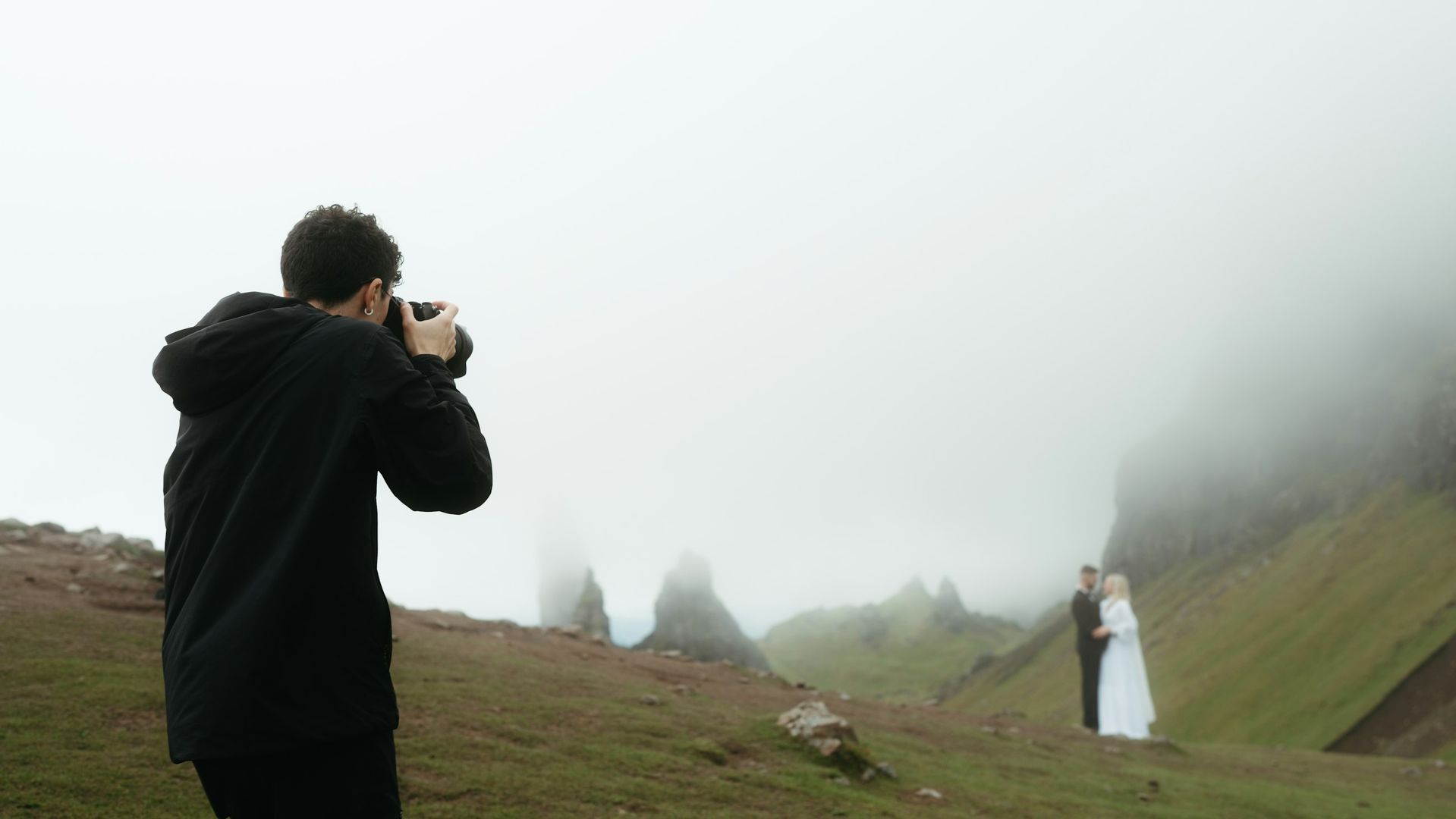 Photographer on a misty hillside making a picture of a couple in the distance
