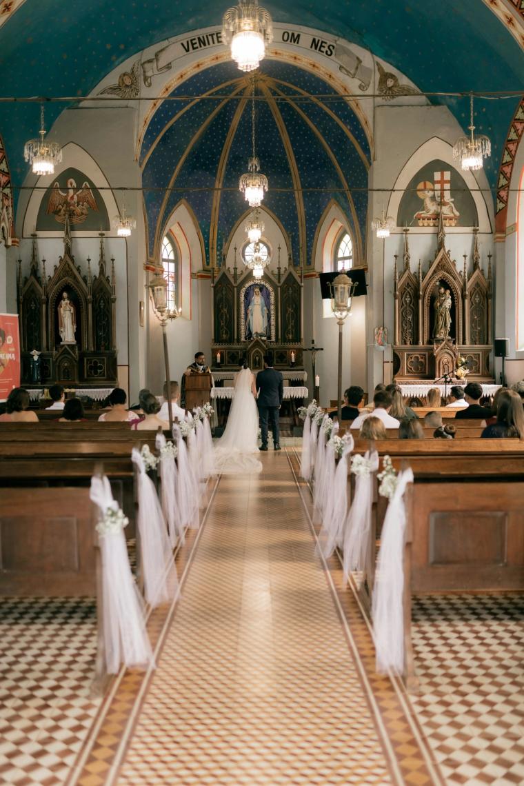 Bride and groom at the altar of a decorated church with guests seated